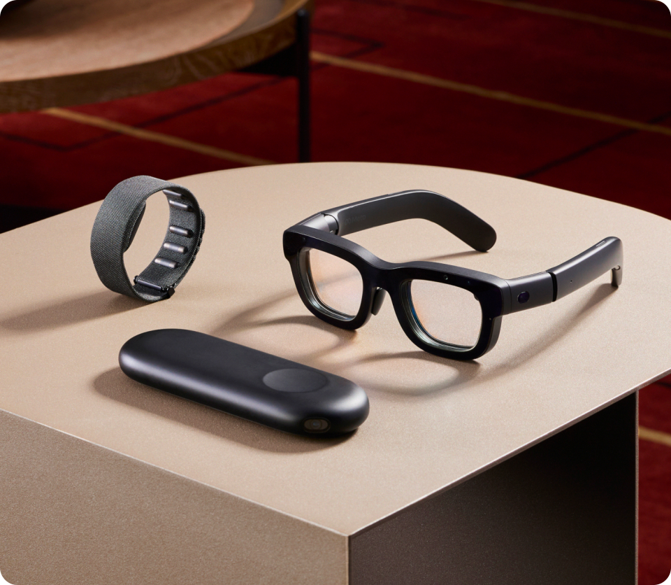 Eine Abbildung der Meta Orion AR-Brille, die elegant und modern gestaltet ist. Die Brille ist auf einem Tisch platziert, die AR-Display-Technologie wird mit holographischen Projektionen dargestellt.